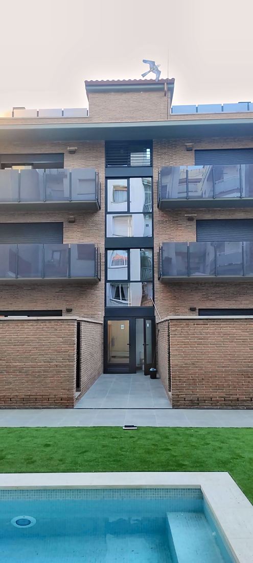 Fachada trasera con el jardín y la piscina comunitaria