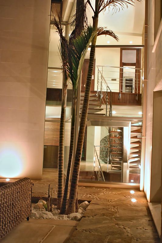 Patio interior de noche con palmera y escalera