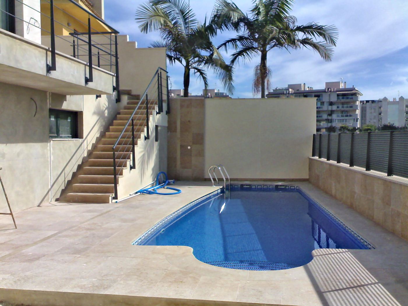 Piscina en el jardín con la escalera exterior y palmeras
