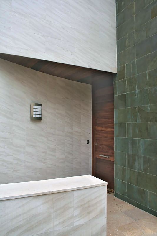 Entrada con puerta de madera junto a un muro de pizarra